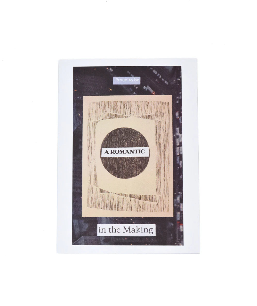 A white greeting card with a photo on the front of a city street from above. A tan wooden design is comped on top. “Proud to be” is in white sans serif font on top. “A Romantic” is in the middle and “In the making” at the bottom both in black serif font - from the Art Assignment