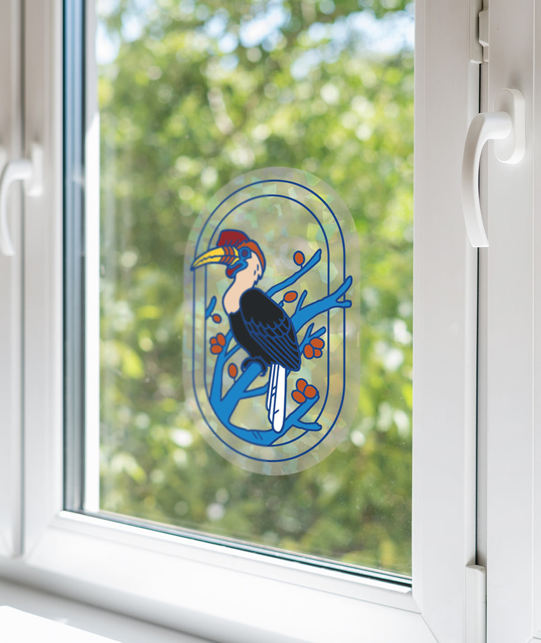 A suncatcher decal with a design of a hornbill on a tree branch. The suncatcher is of a cracked ice holo pattern. The decal is placed onto a glass window. From Bizarre Beasts.
