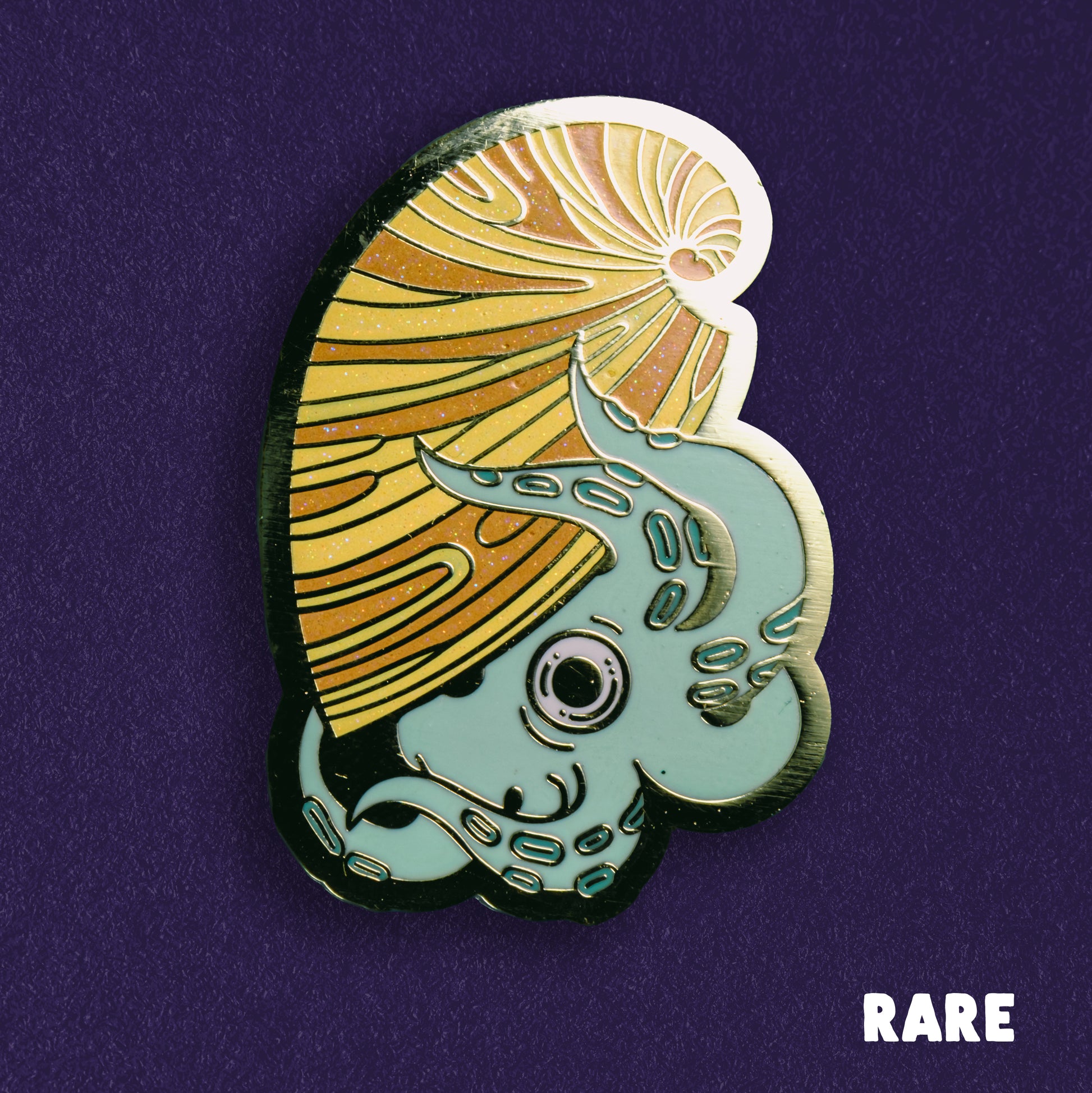 A photo of a soft enamel pin featuring an argonaut on a purple background. It is light blue and yellow with gold metal plating. Rare