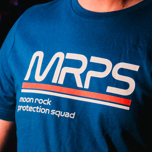 A close up of someone wearing a blue t-shirt with a text-based design on the chest. The design reads "MRPS" in big text and "moon rock protection squad" in smaller text underneath it. From SciShow.