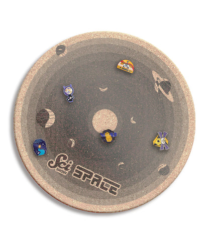 A round cork board with shades of gray, showing the different planets with different Scishow Space pins attached. It says "Scishow Space" on the outer edge.